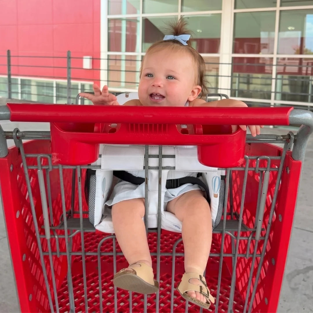Child sitting in a red shopping cart with a blurred background