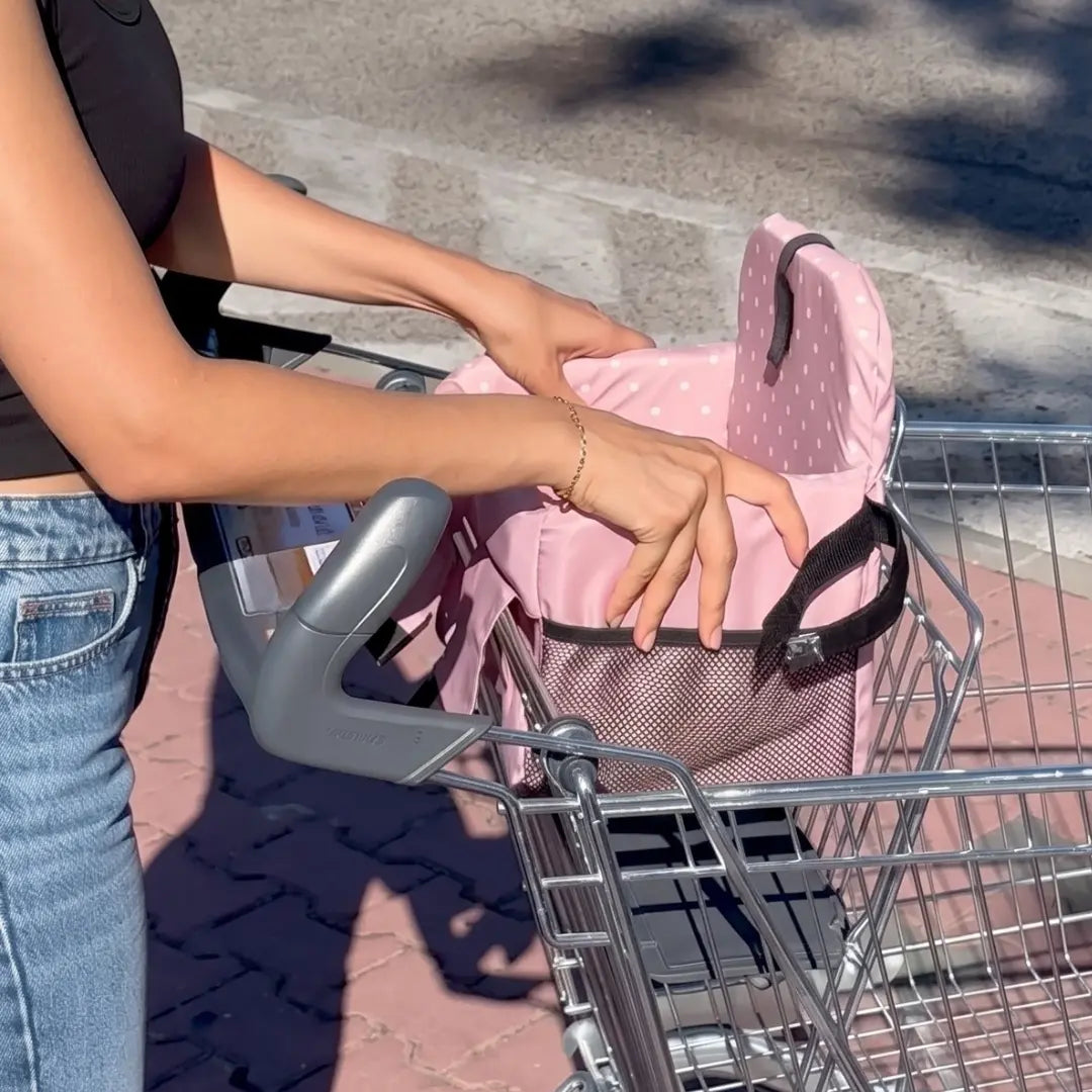 Coco Comfort Seat in pink polka dot pattern, being placed inside a shopping cart handle