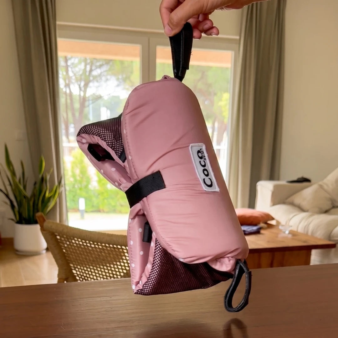Coco Comfort Seat in pink polka dot pattern, folded up and held indoors
