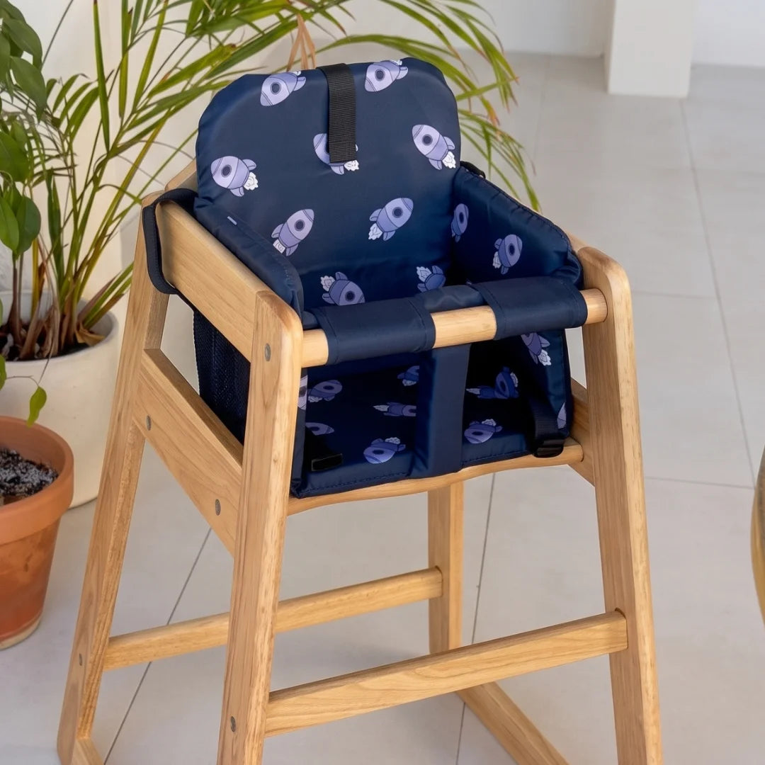 Coco Comfort Seat in navy blue astronaut pattern, installed inside a wooden high chair