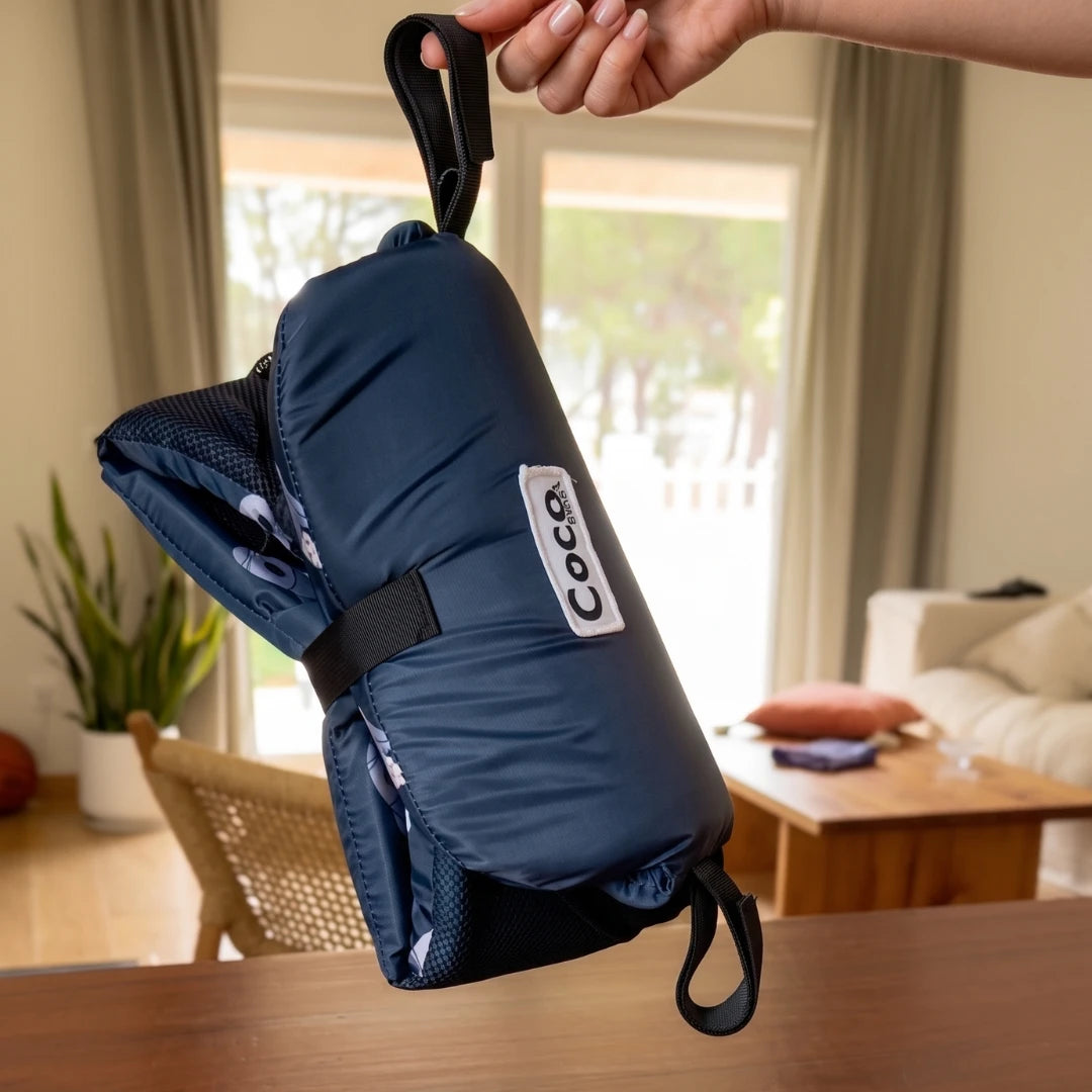 Coco Comfort Seat in navy blue astronaut pattern, folded up and held indoors
