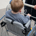 Toddler seated in Cocoseat cart insert, rear view showing securing straps and mesh pocket