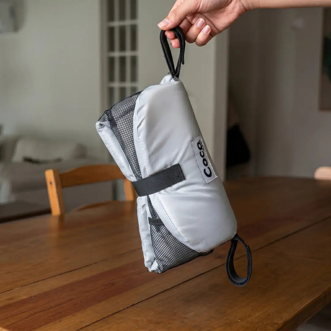 Coco Comfort Seat folded into its carry
pouch next to a diaper bag