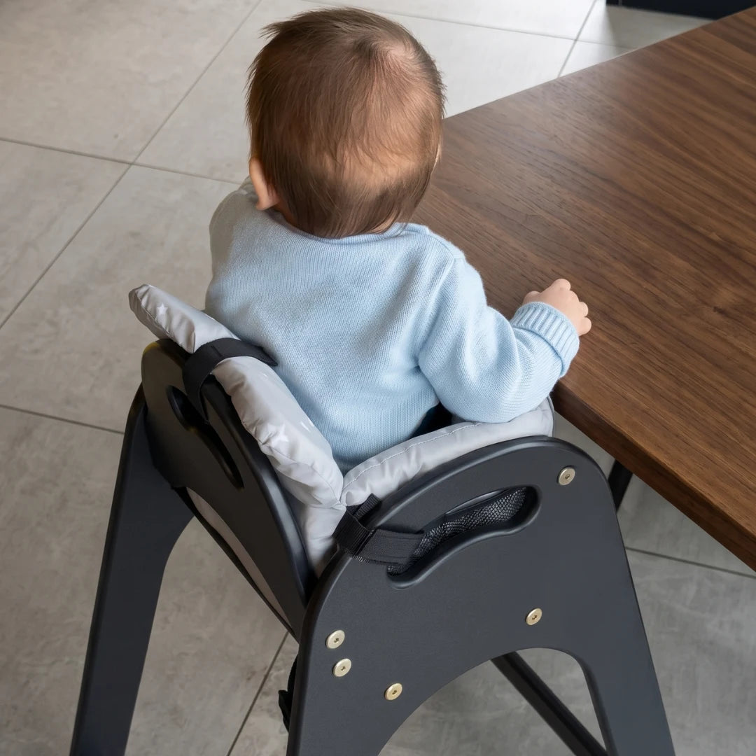 Child sitting in a high chair at a wooden table