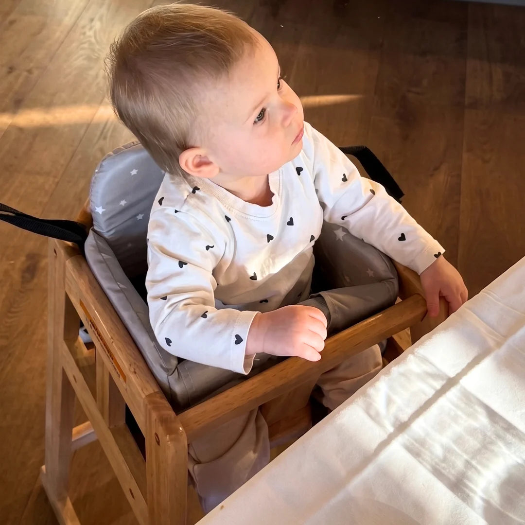 Child sitting in a high chair at a dining table